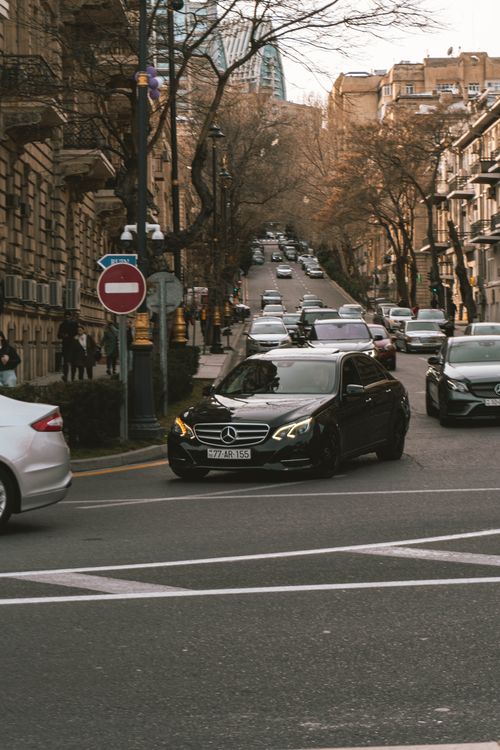 Free A bustling city street with vehicles navigating traffic amidst urban architecture in the fall. Stock Photo