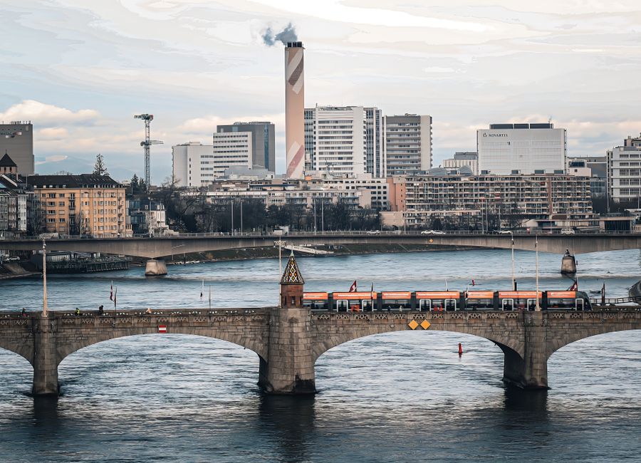 Aerial view of Basel, Switzerland featuring the Middle Bridge with a train crossing, city skyline and river.