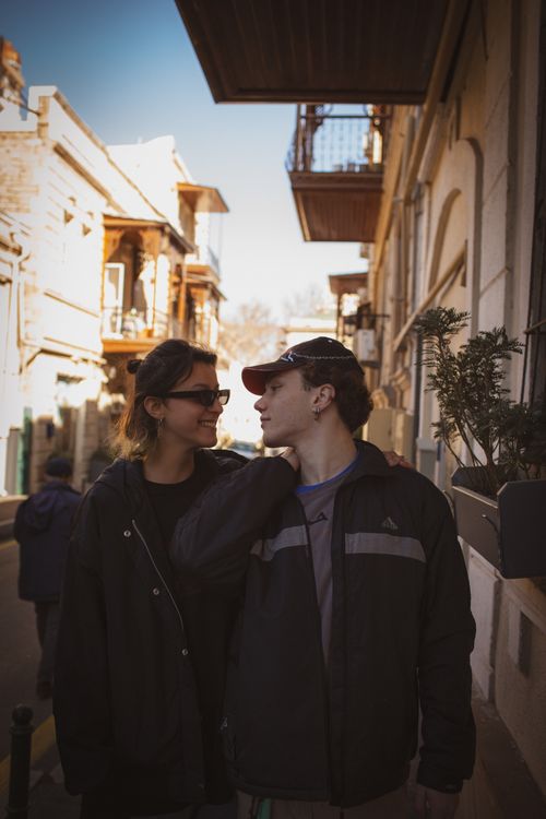 Free A young couple enjoying a casual stroll together in a sunny urban street. Stock Photo