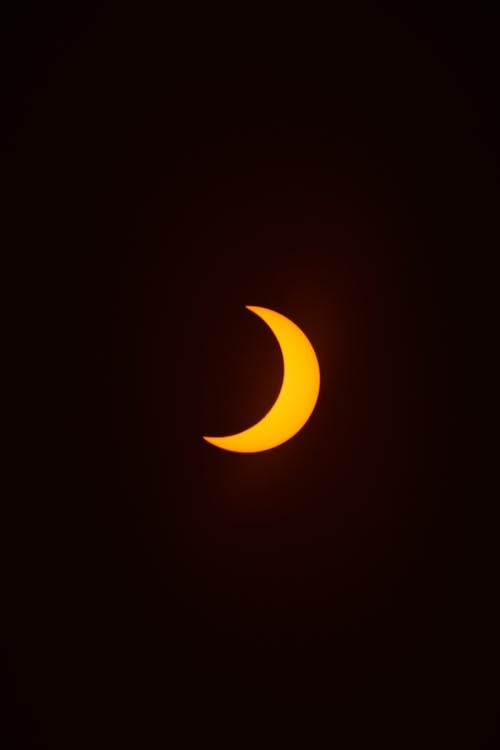 View of an Orange Crescent Moon against Dark Night Sky 