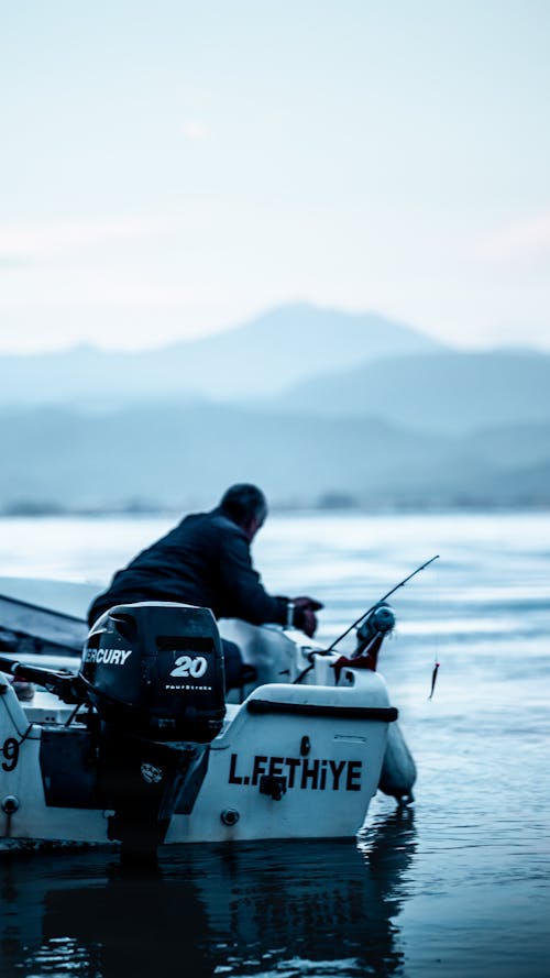 A man is fishing on a boat in the water