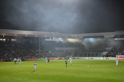 A soccer match is played in a stadium with smoke