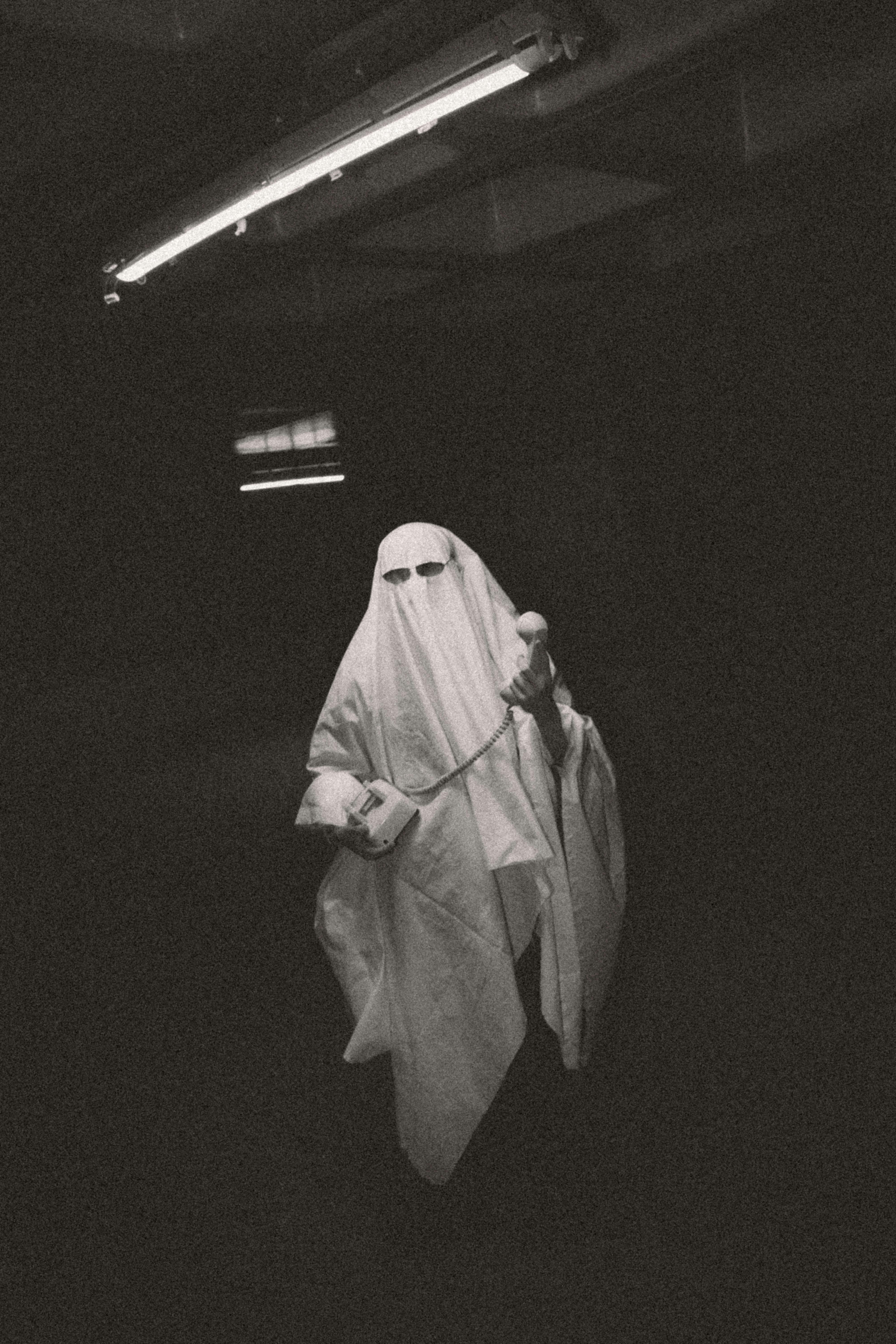 A spooky ghost costume with a microphone in an eerie black and white setting.