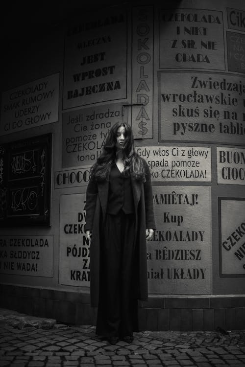 A woman in black standing in front of a wall of signs