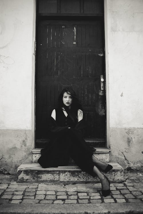 Woman Sitting on Stairs by Door in Black and White
