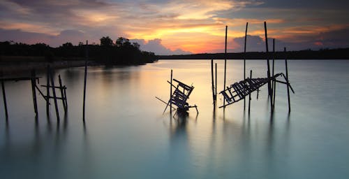 Free 夕阳下的水体上破碎的木板路的剪影 Stock Photo