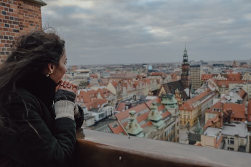 A woman looking out over a city with a view of the buildings