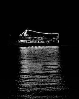 夜晚，一艘明亮的船在平静的河面上投下美丽的倒影