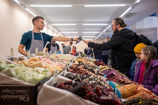 People browsing and buying colorful sweets at an indoor market in Wrocław, Poland. Perfect stock for urban lifestyle themes.