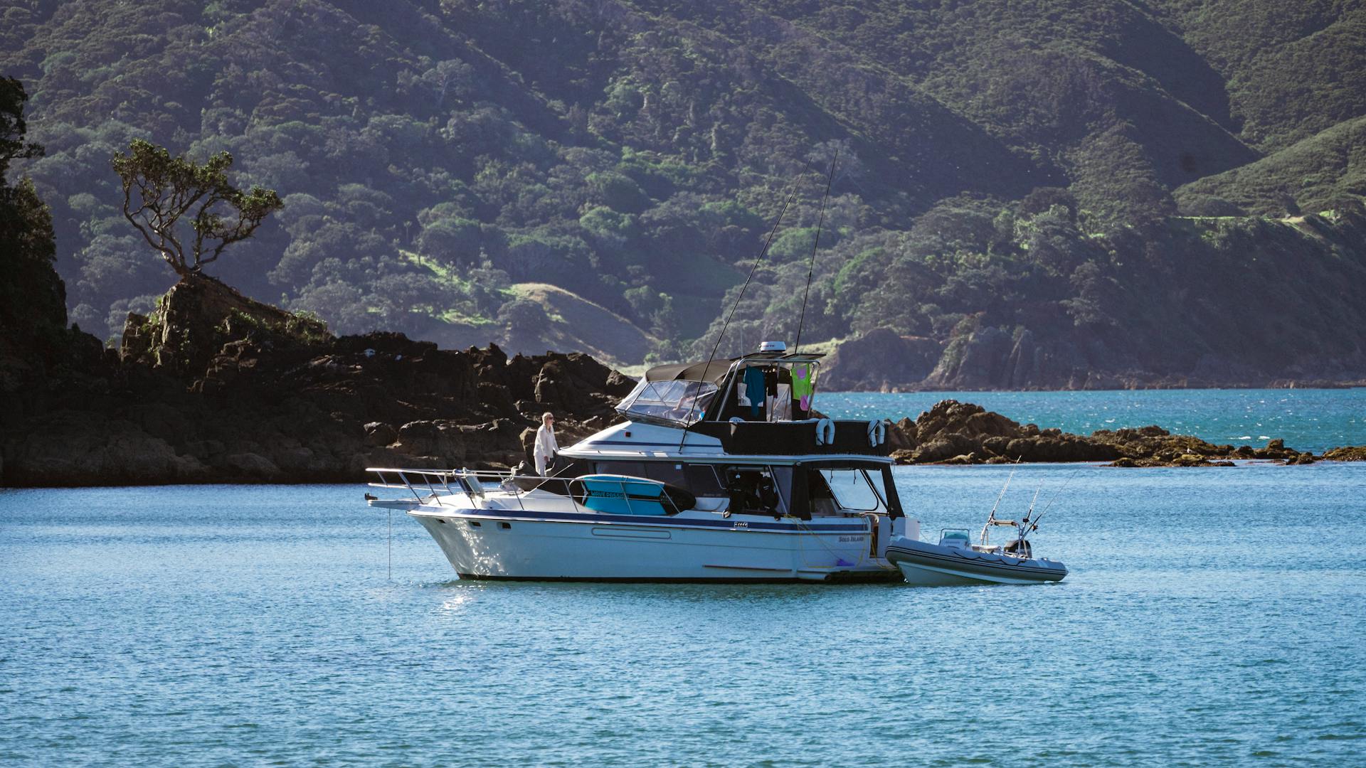 A serene scene of a luxury yacht anchored in a picturesque bay against lush hills.