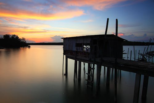 Siluetta Della Casa In Cima All'acqua Dell'oceano Durante Il Tramonto