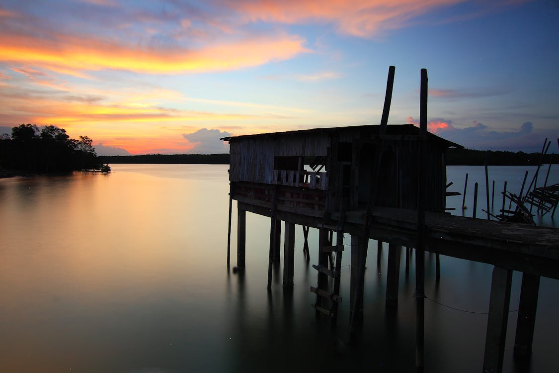gratis Silhouet Van Huis Bovenop Oceaanwater Tijdens Zonsondergang Stockfoto