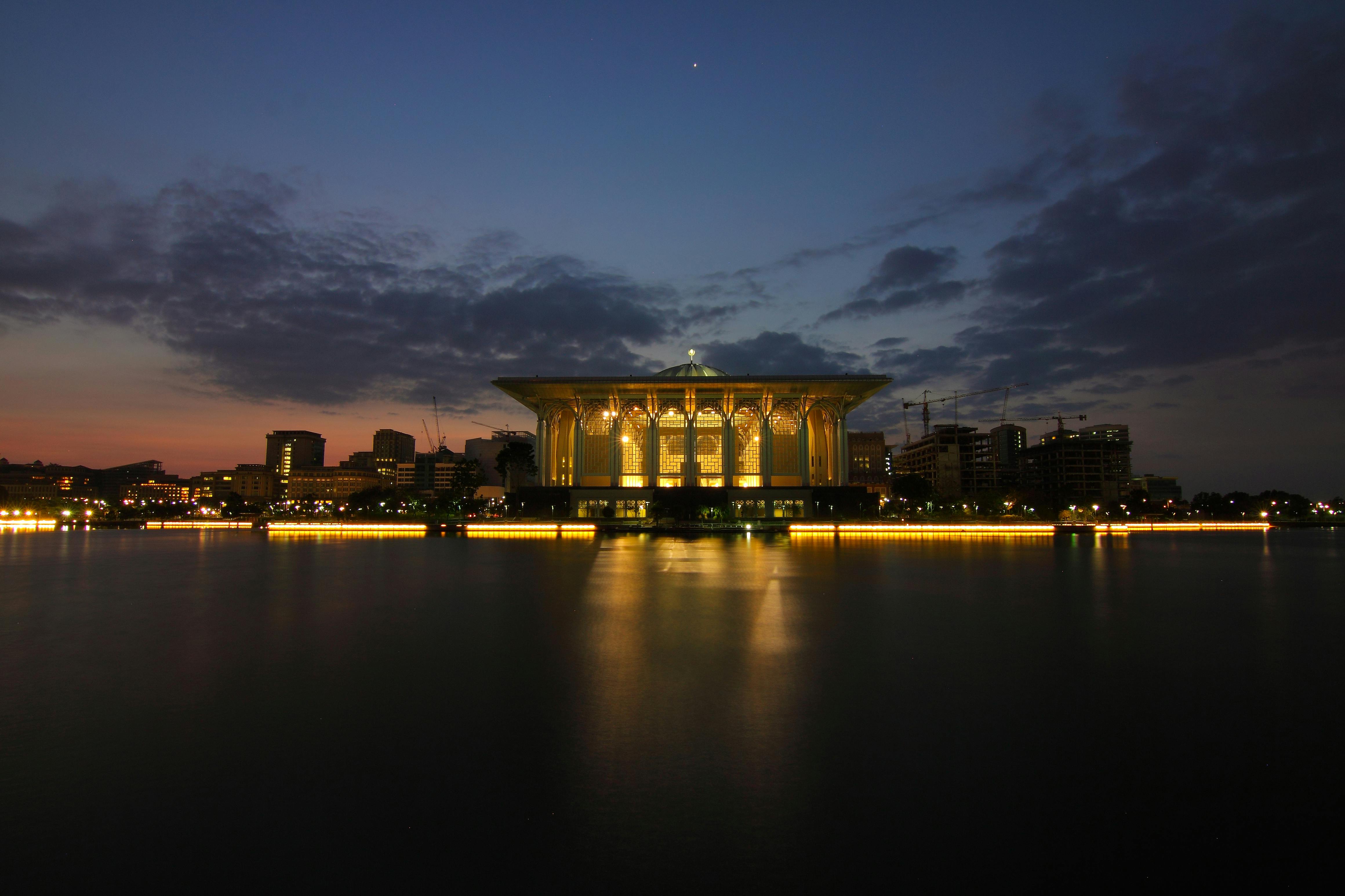 宁静的夜间城市景观中，灯光照明的建筑物在黑暗的天空下倒映在平静的水面上