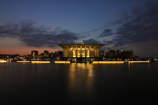宁静的夜间城市景观中，灯光照明的建筑物在黑暗的天空下倒映在平静的水面上