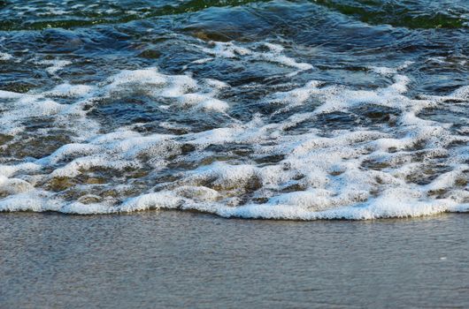 Peaceful ocean waves with foamy crests touching the sandy beach, capturing nature's tranquility.
