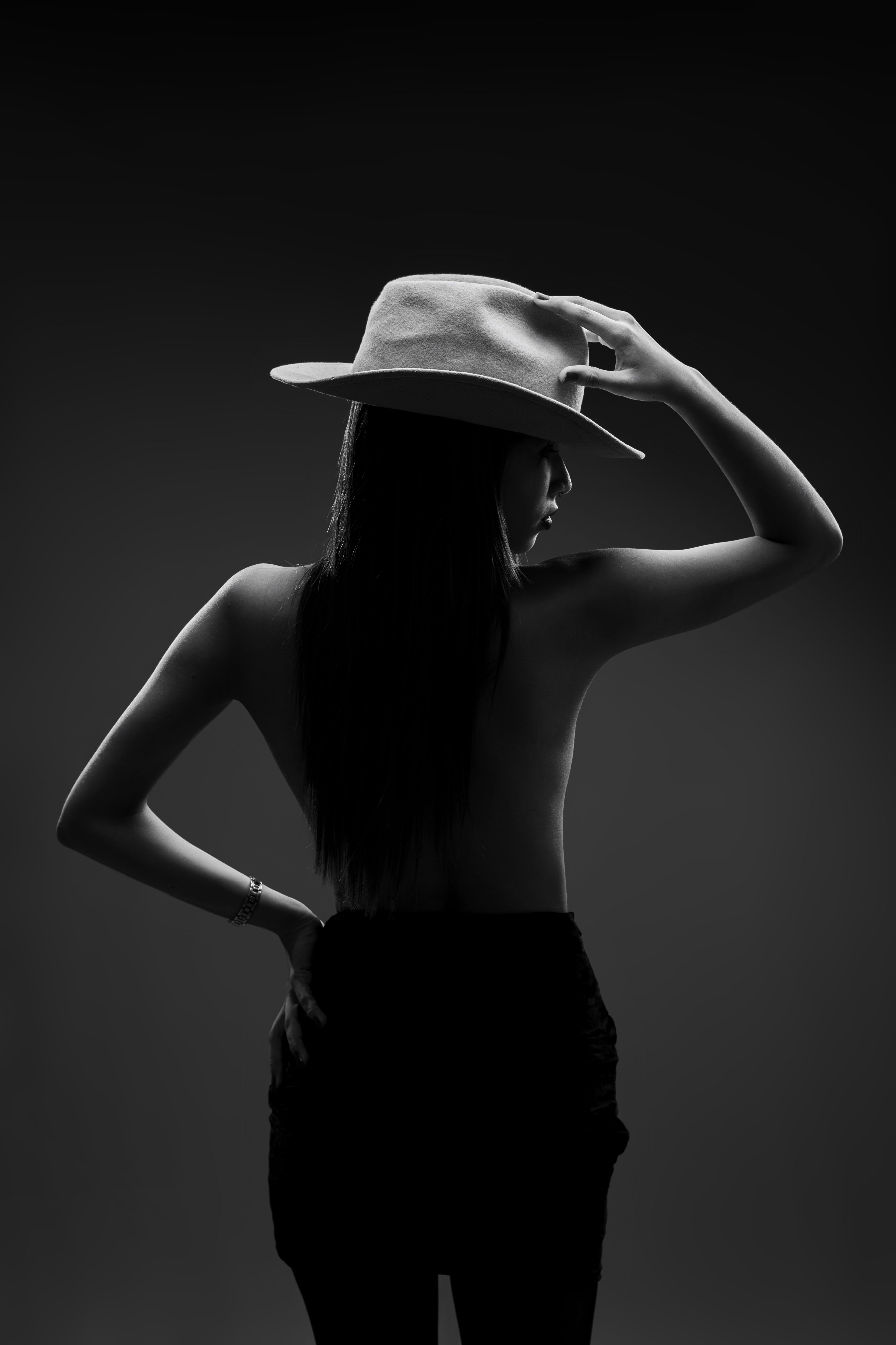 Artistic black and white portrait of a woman in studio, highlighting elegance and mystery.