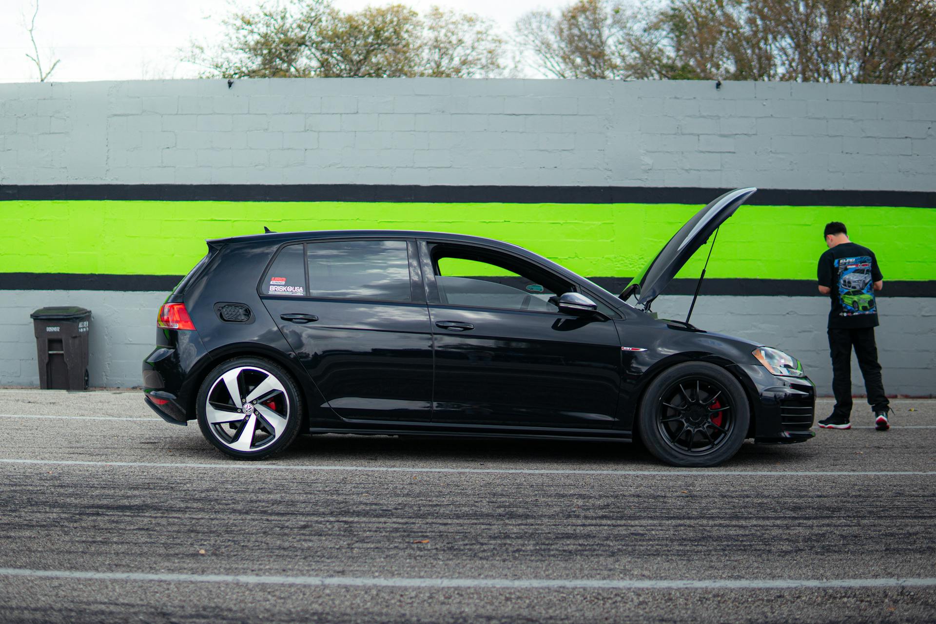 Driver in Front of a Black Volkswagen Golf GTI with Open Hood