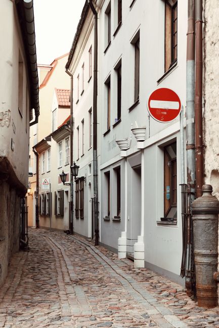 Serene cobblestone street in Old Town Riga, showcasing historic architecture and a no entry sign.