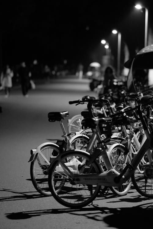A black and white photo of bicycles parked at night