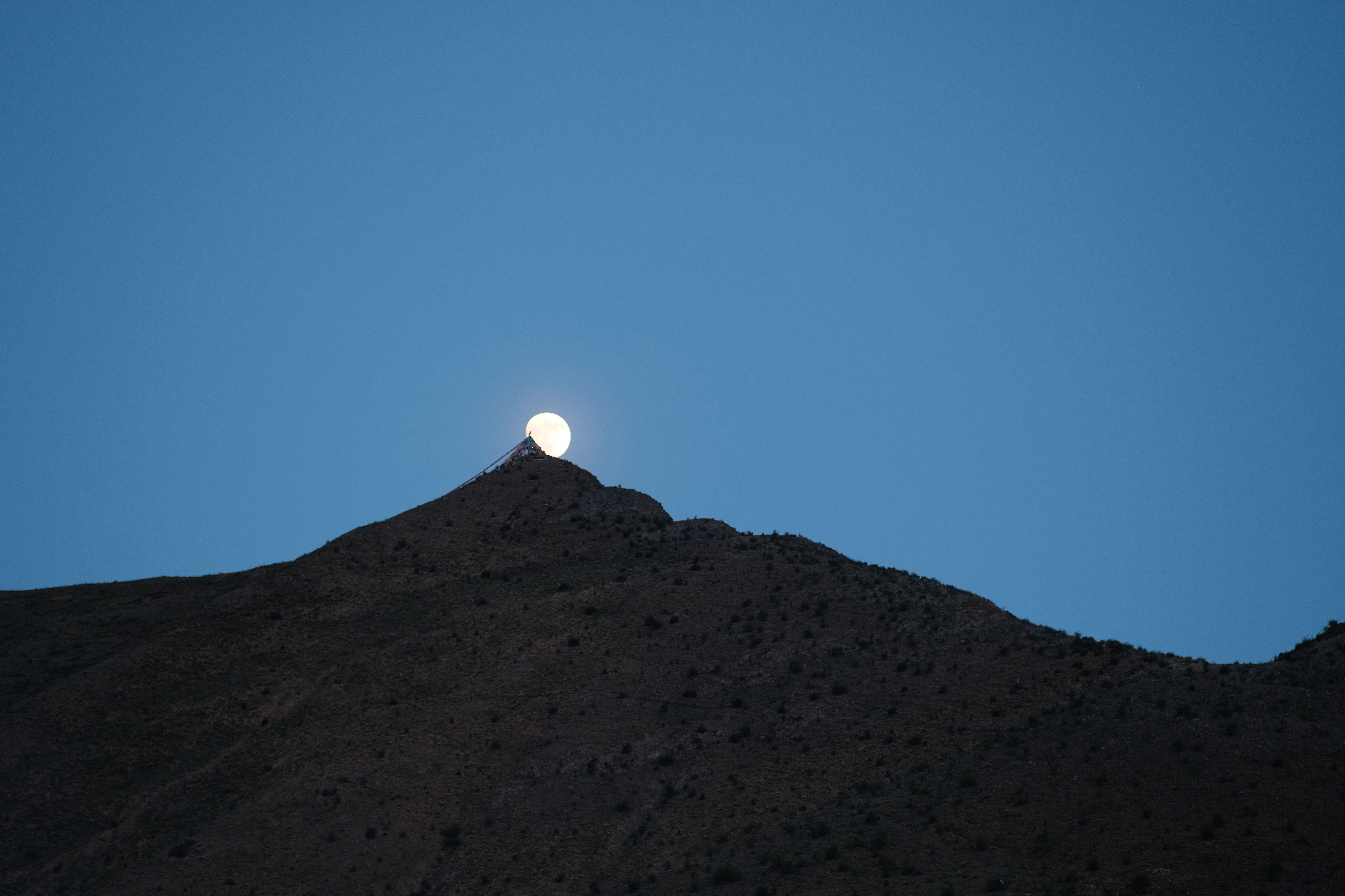 The moon rises over a mountain top · Free Stock Photo