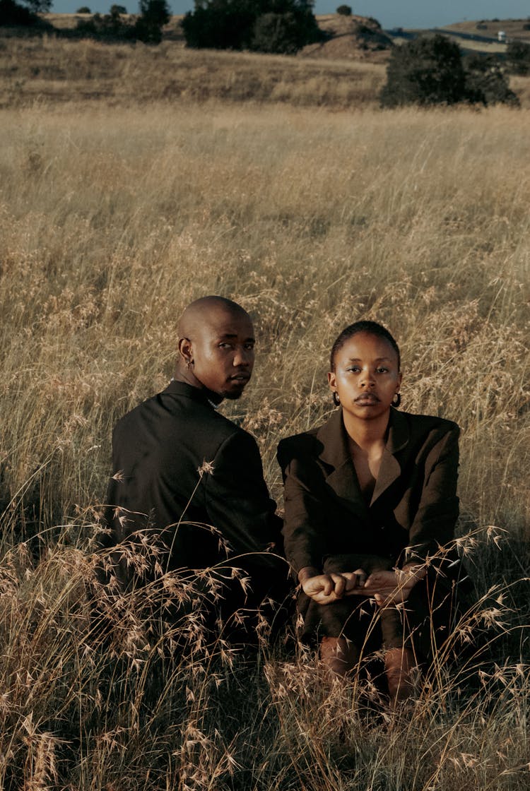 Couple Sitting On Rural Field