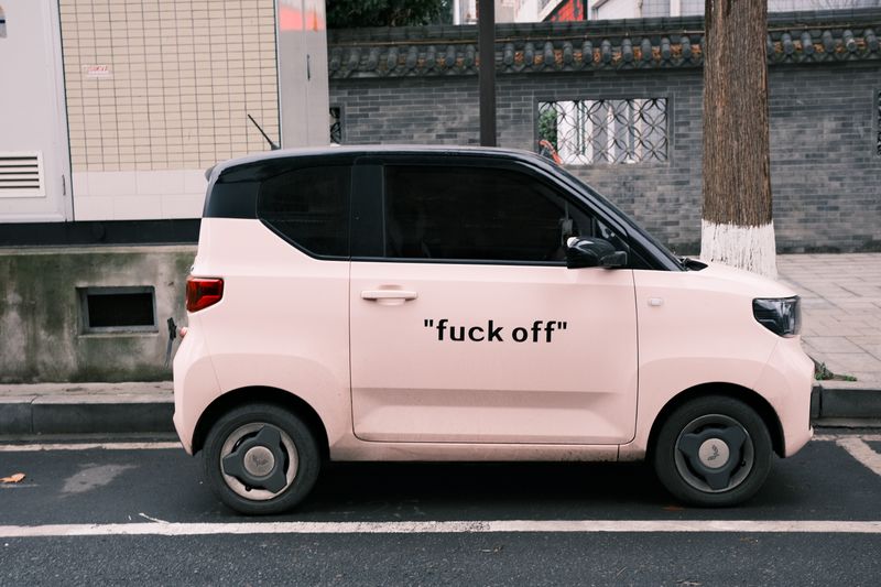 A pink Wuling Hongguang Mini EV city car parked on a Chinese urban street, showing the compact electric car segment the Smart #2 enters
