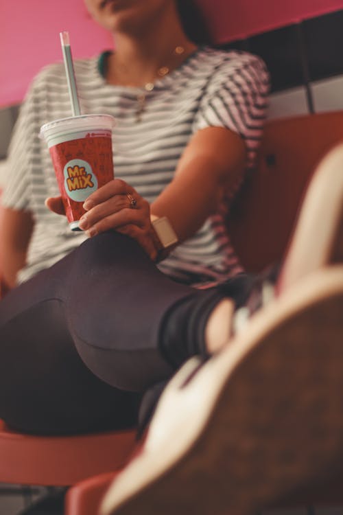 Photo of Woman Holding Mr. Mix Plastic Milkshake Cup While Sitting