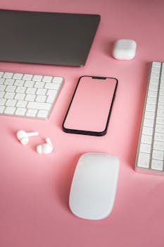 Stylized arrangement of electronic devices on a vibrant pink background, ideal for tech marketing.