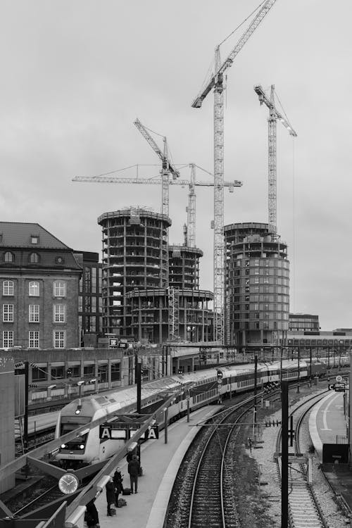 A black and white photo of a train station with construction cranes