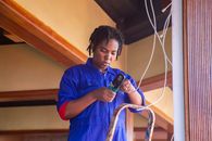 Professional electrician working on wiring in an indoor setting, demonstrating skill and concentration.