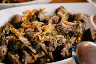 Close-up of a flavorful beef stir-fry with mixed vegetables in a white serving dish, perfect for dinner.