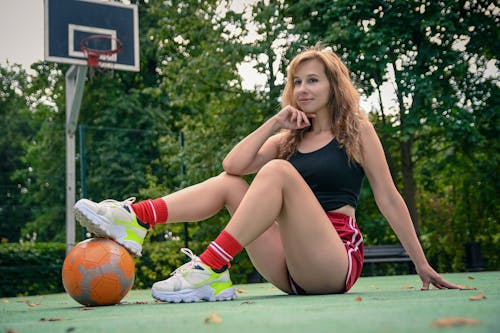 A woman sitting on the ground with a soccer ball