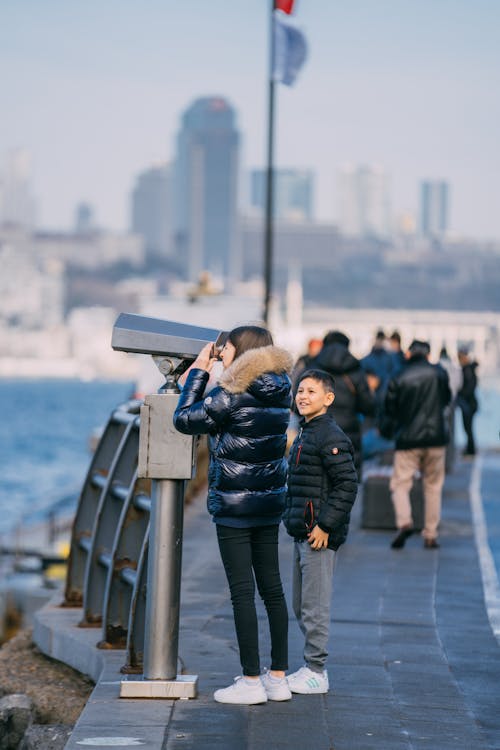 A young boy and girl looking at binoculars on the waterfront