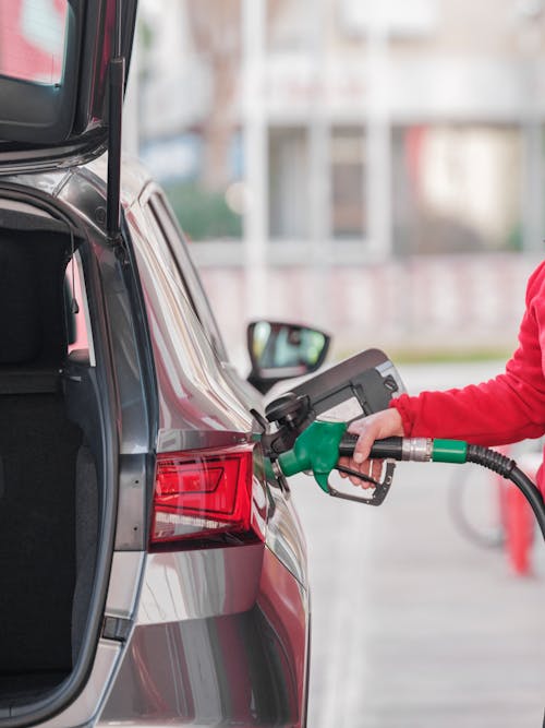 Pumping gas at gas pump. Closeup of man pumping gasoline fuel in car at gas station.