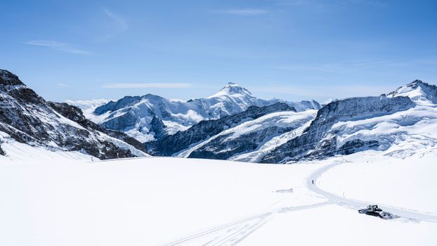 Stunning view of a snowcapped alpine mountain range with a bright blue sky, perfect for winter landscapes.