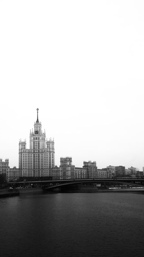 Free A striking black and white cityscape showcasing a tall skyscraper near a waterfront in an urban setting. Stock Photo