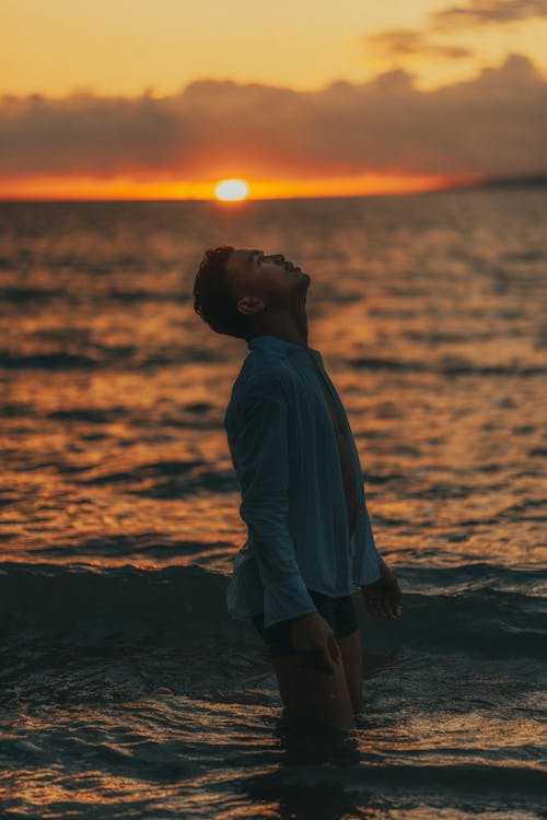 Man in White Shirt Standing in the Sea at Sunset