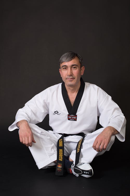 A man in black and white karate gear sitting on the ground