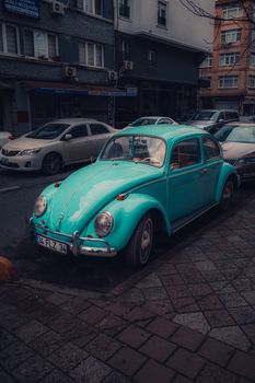 Classic turquoise car parked on a city street, capturing urban nostalgia.