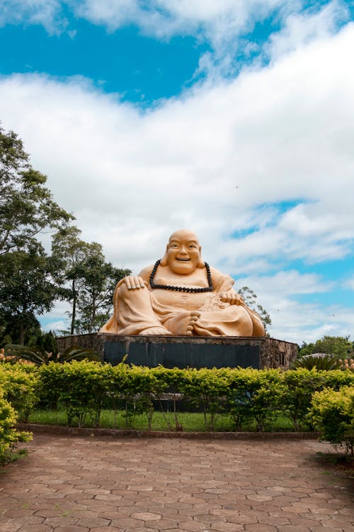 A large buddha statue sitting in the middle of a park