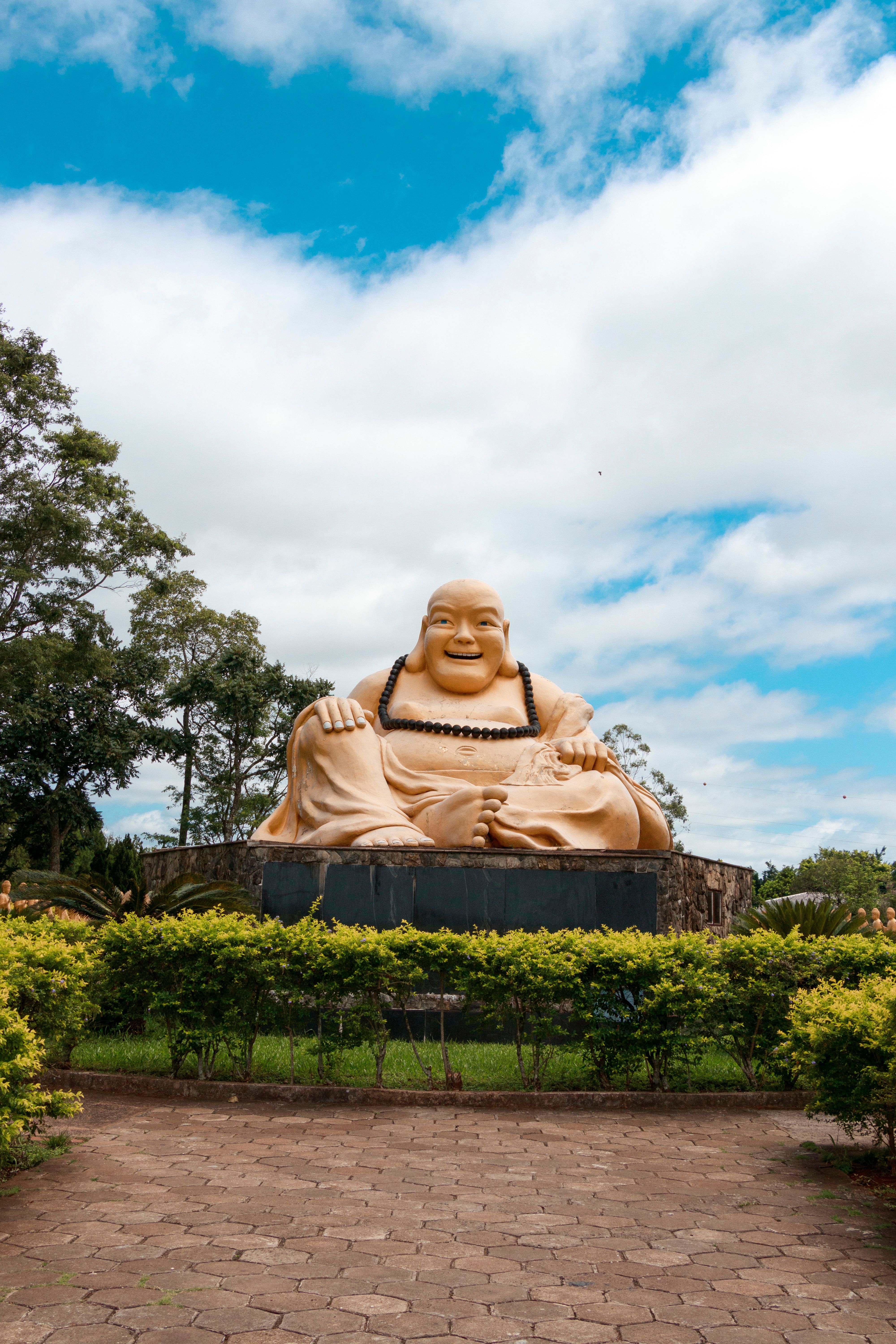 A large buddha statue sitting in the middle of a park · Free Stock Photo