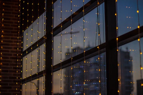 A window with lights and a city skyline in the background