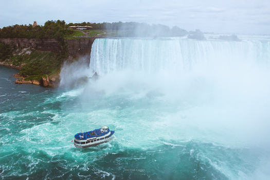 A stunning aerial shot of Niagara Falls with a tour boat navigating the misty waters.