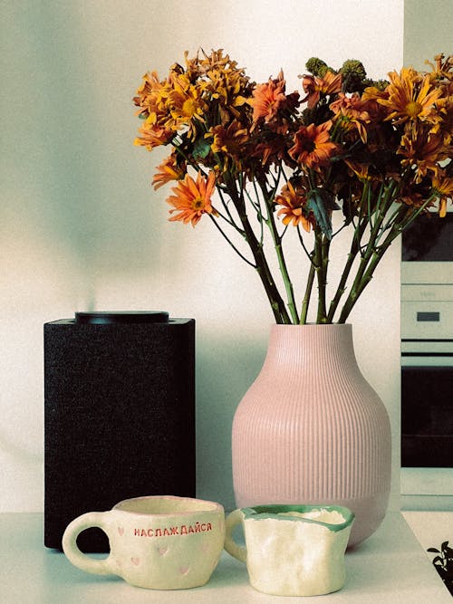 A vase with flowers in it and a coffee mug