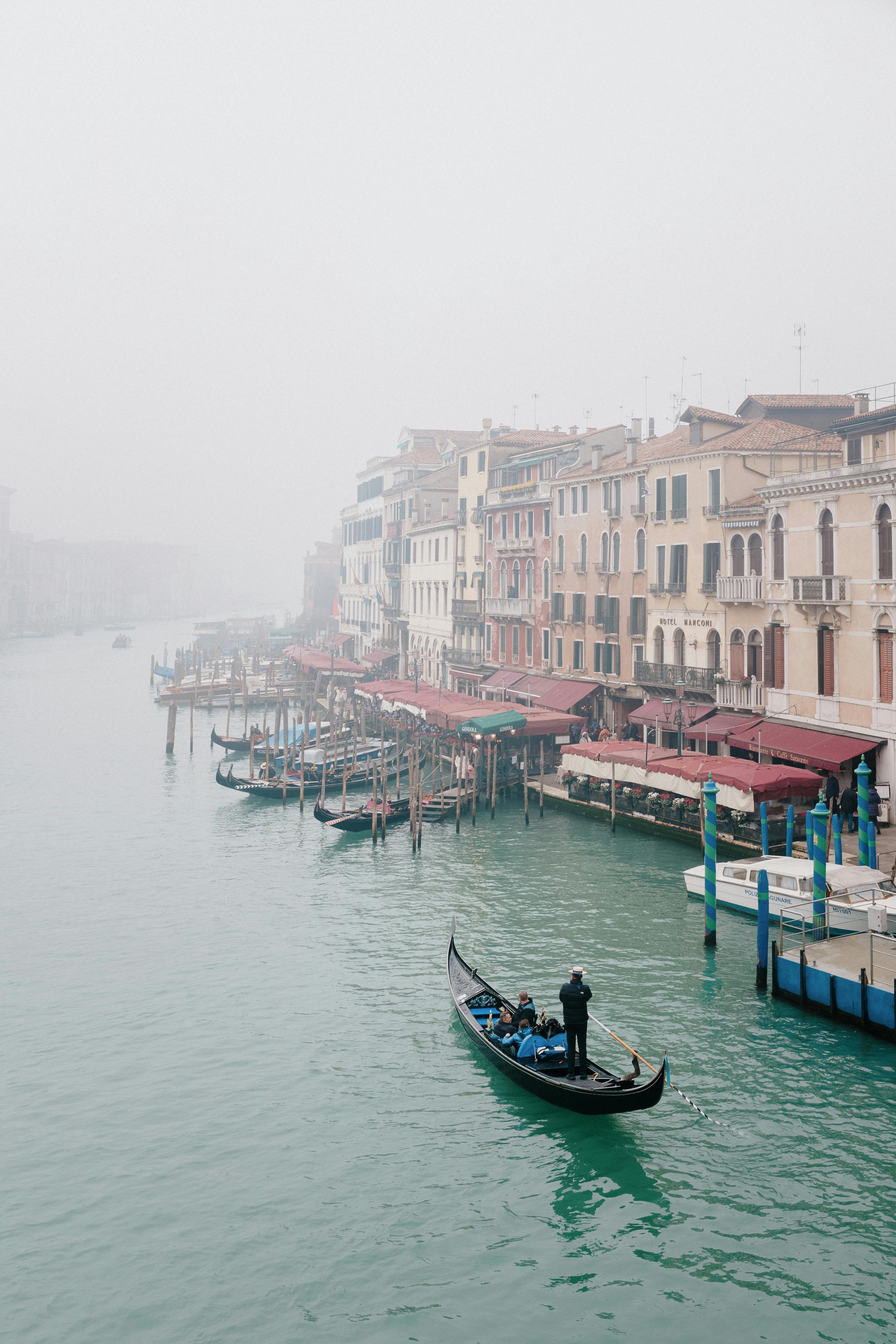 A gondola glides through a misty canal in Venice, Italy, surrounded by historic buildings.