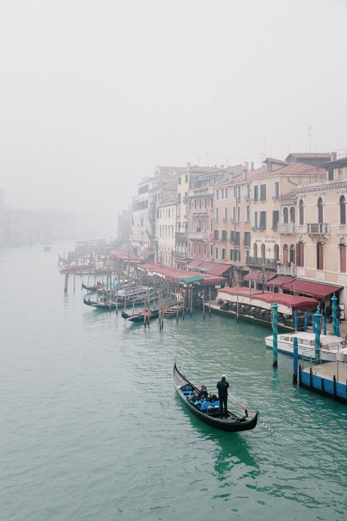 Free A gondola glides through a misty canal in Venice, Italy, surrounded by historic buildings. Stock Photo