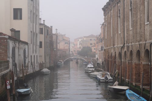 A canal in a foggy city with boats on it