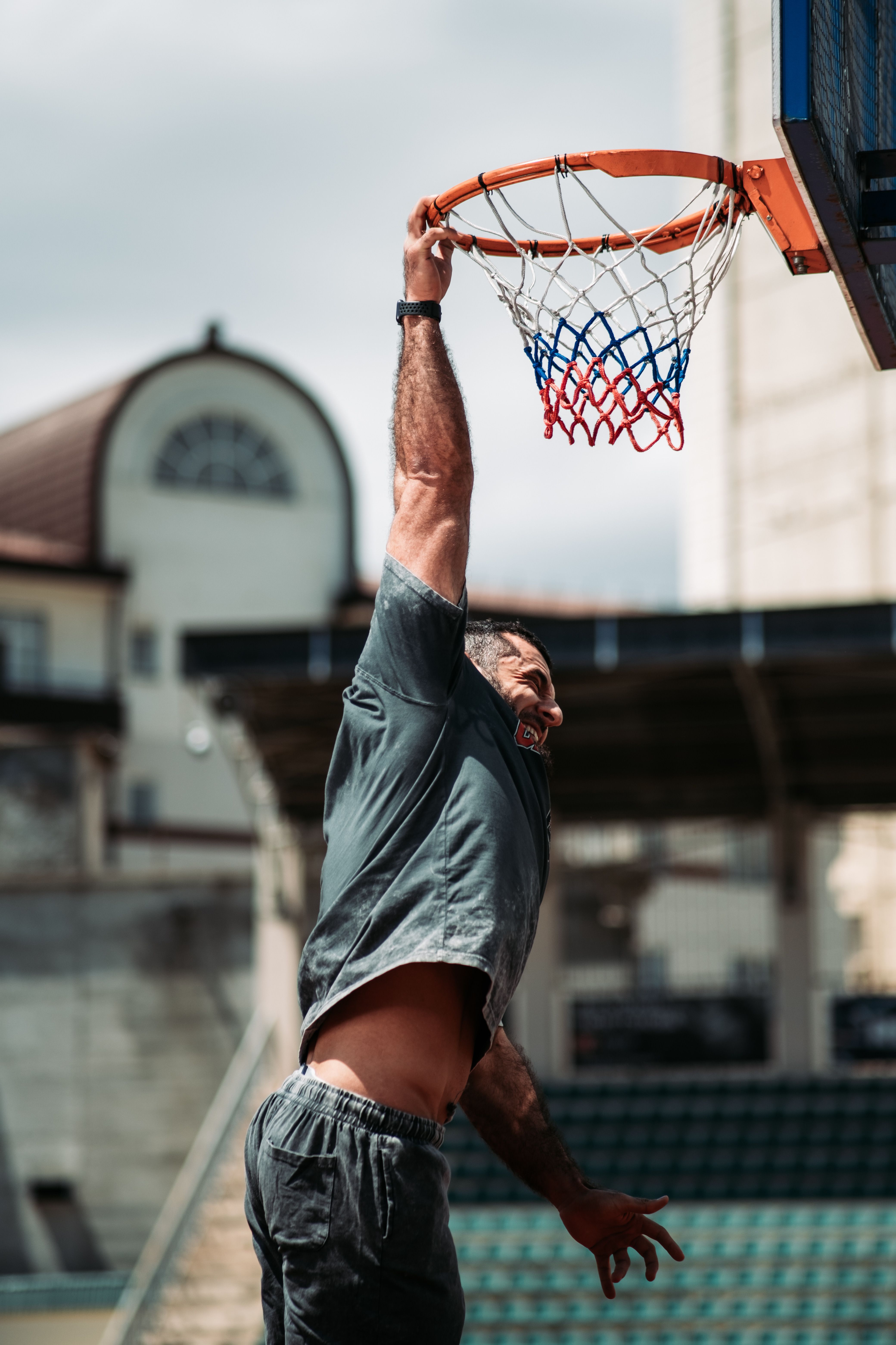 Athlete performing an energetic dunk on outdoor basketball court