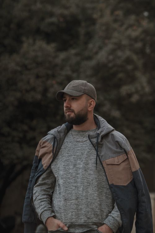 Free A bearded man wearing a sweater and jacket outdoors, embodying casual fashion style. Stock Photo