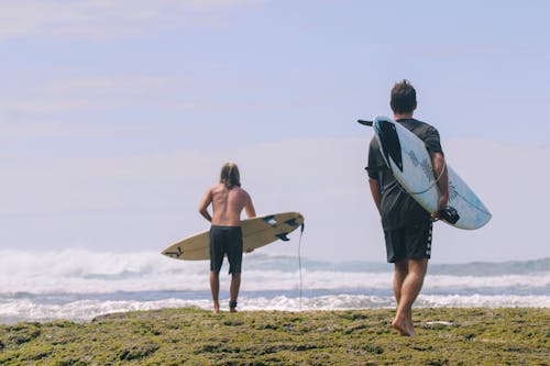 Two men walking on the beach with surfboards